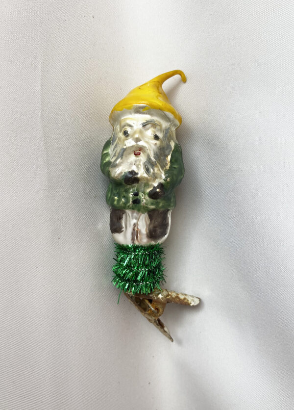 1940s German glass gnome dwarf clip on christmas ornament, with yellow pointed hat and green coat, tuchsheer greenery wrapping the coil cup.